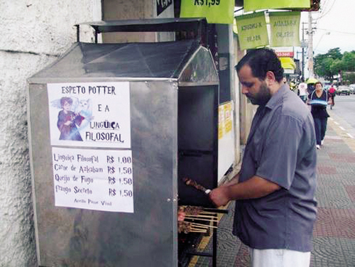 Barraquinha de churrasco de rua com o nome "Harry Potter e a linguiça filosofal".
Um desenho bem simples mostra o personagem segurando um espetinho. No cardápio, espetinhos variando de 1 real a 1,5 tem nomes como "Linguiça Filosofal" ou "Carne de Askaban". Os outros nomes dos espetinhos também fazem referência a série, mas não consigo ler direito porque a imagem está em baixa qualidade.